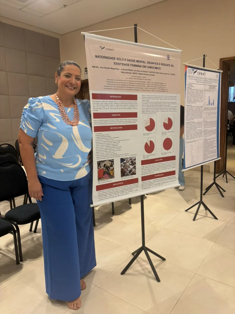 Estudante ao lado do banner apresentado no congresso
